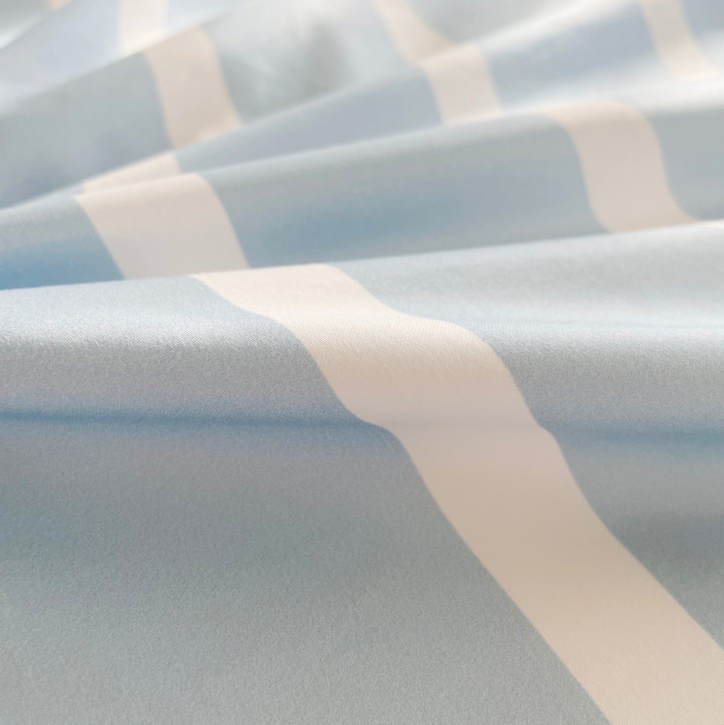 A close-up of soft, breathable blue and white striped pure cotton fabric, showcasing its smooth texture and high-quality weave. The fabric’s gentle feel and durability make it perfect for a cozy and comfortable bedding experience.