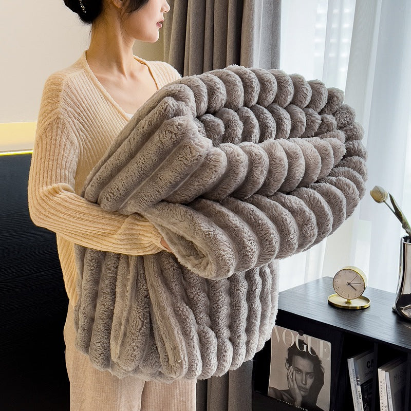 Thick grey blankets for winter, held by a woman, providing extra warmth and comfort during the cold season with a soft, cozy texture.