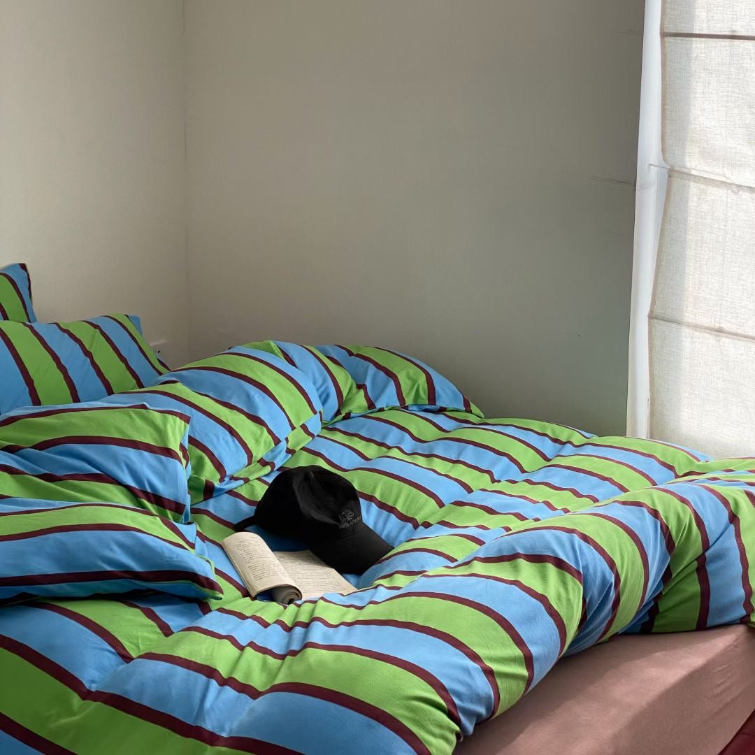 Blue and green striped bedding set made from soft cotton jersey knit sheets, combining comfort and vibrant style for a cozy bedroom.