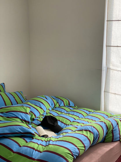 Blue and green striped bedding set made from soft cotton jersey knit sheets, combining comfort and vibrant style for a cozy bedroom.